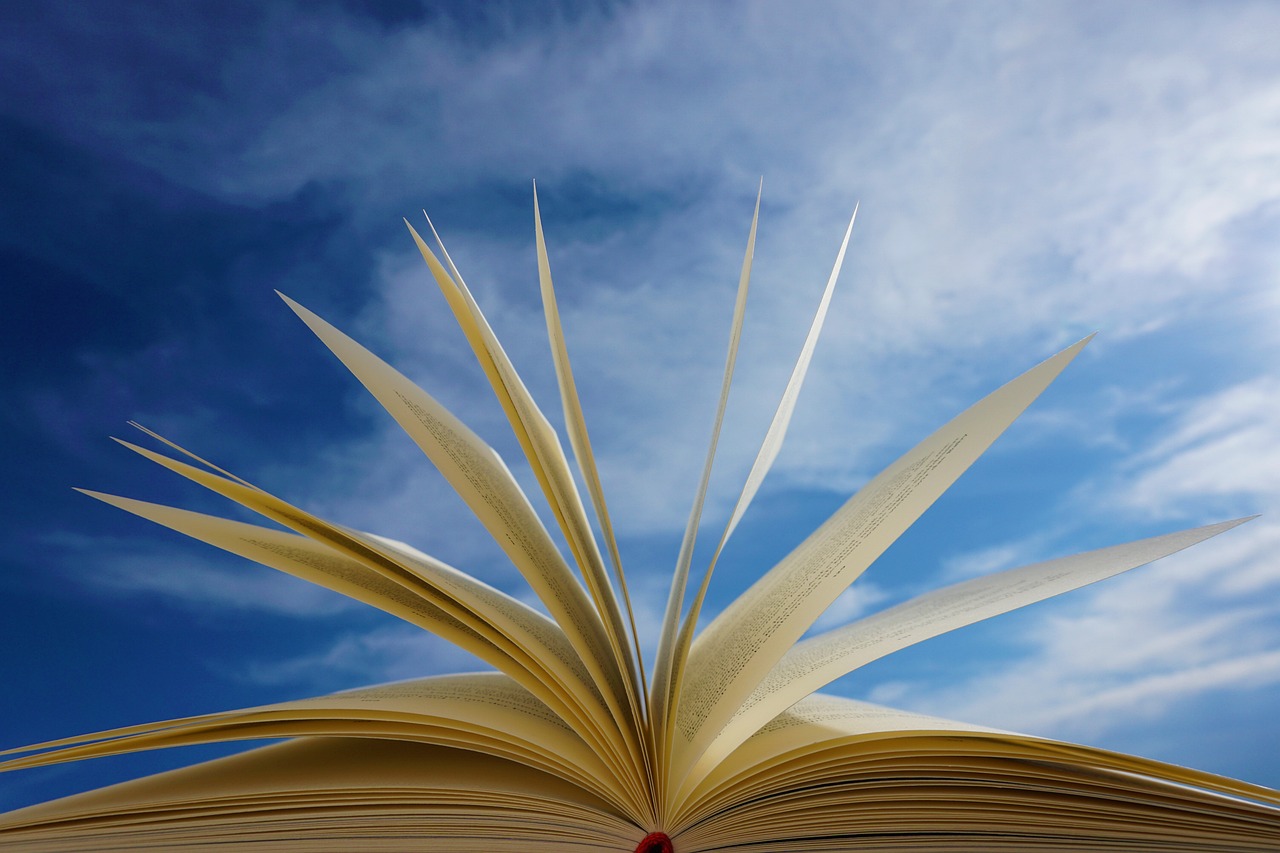 Beige book pages flipping open towards a blue sky.